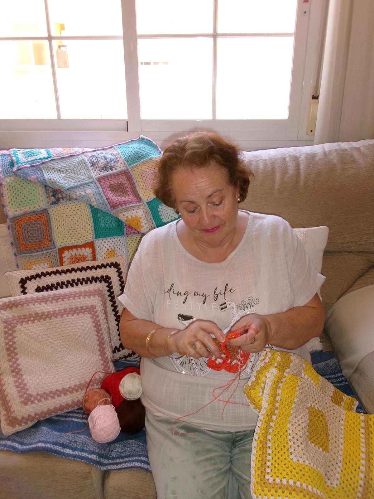 Clemencia tejiendo en su hogar
